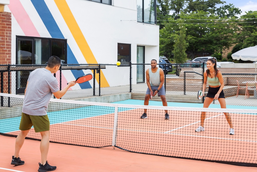 three people playing pickleball