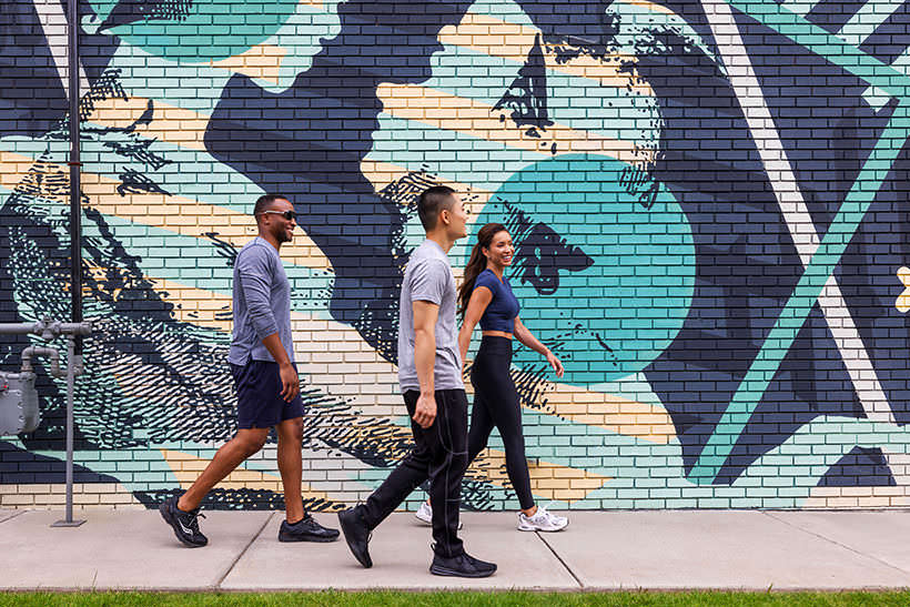 people walking by a building mural